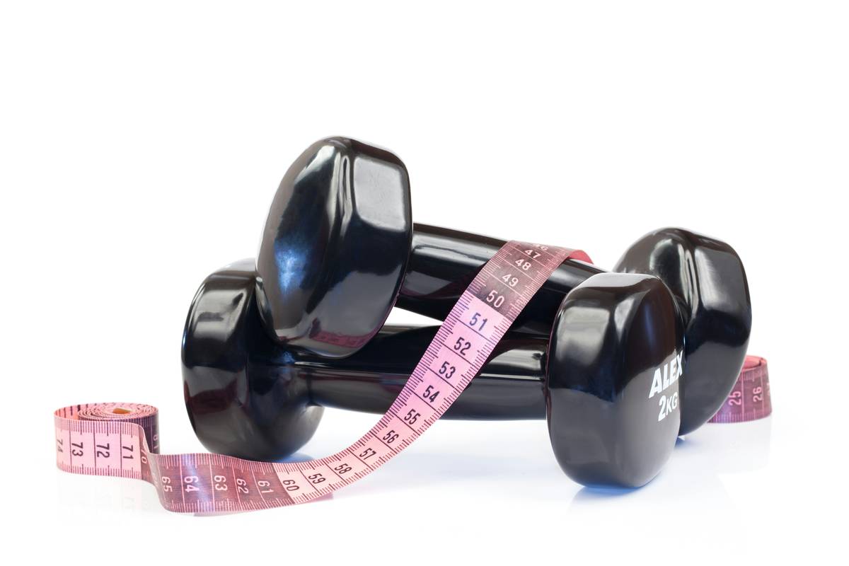 woman tracking weight loss diet exercise ratio with journal and dumbbells